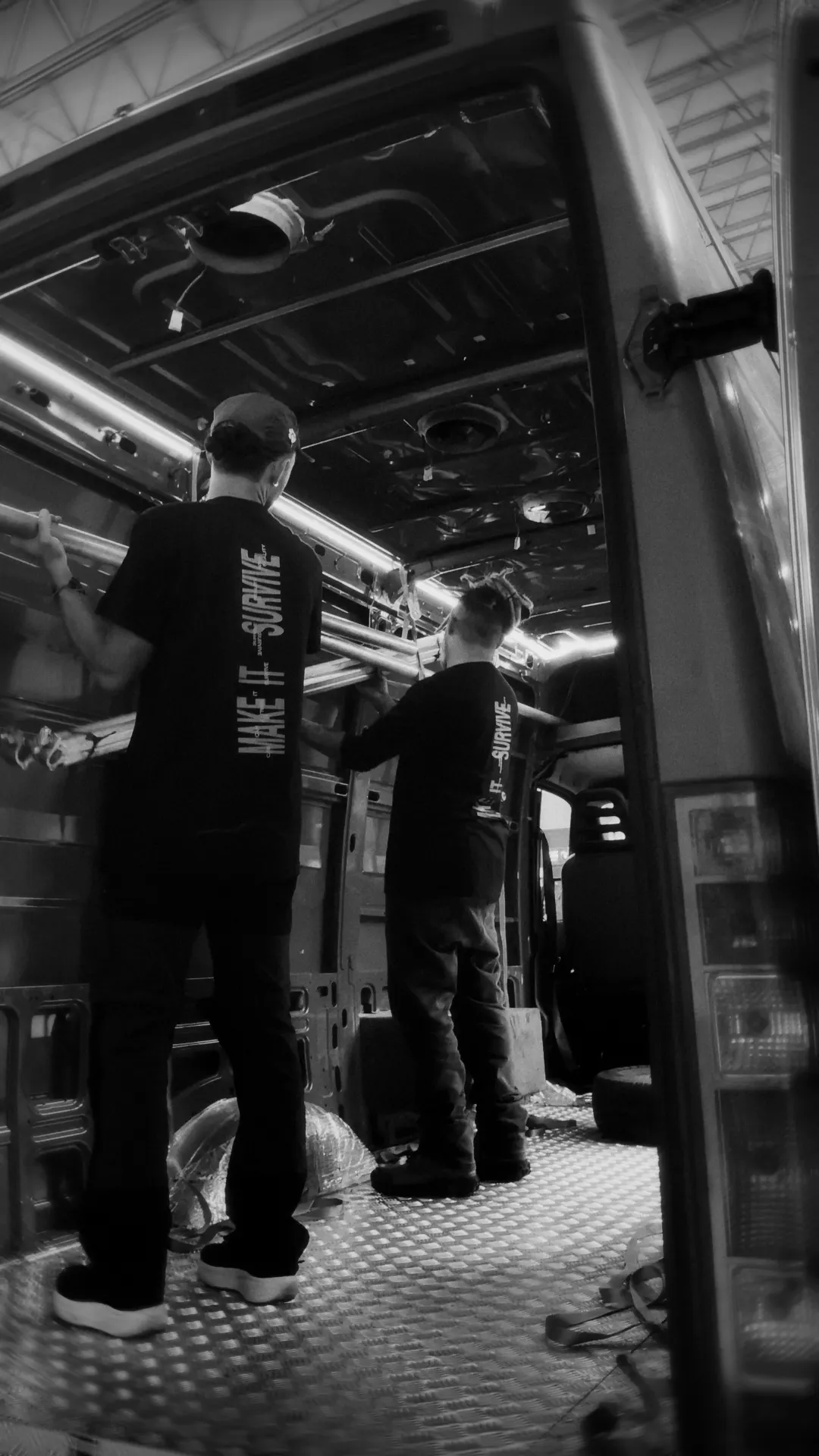 Equipe montando o set dentro de uma van, com a camiseta Make it survive