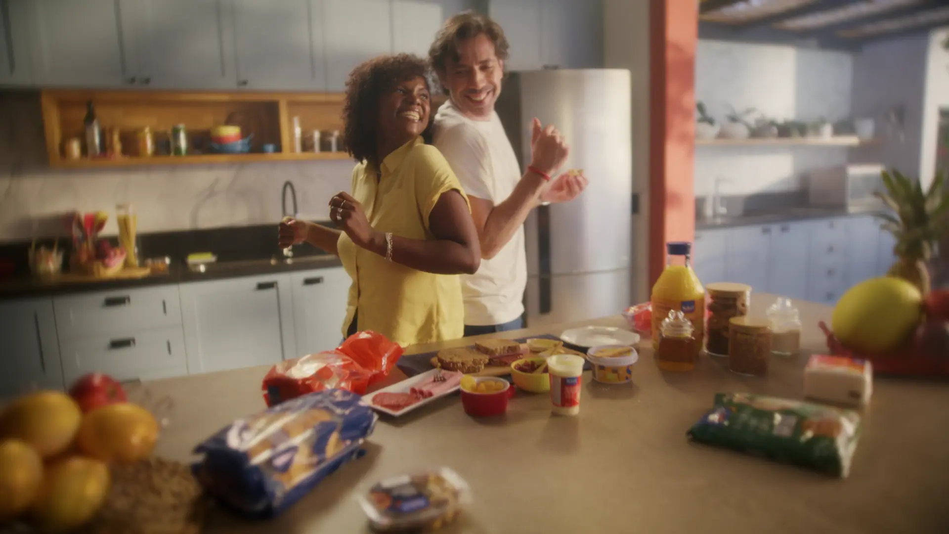 Casal dançando na cozinha, com as compras em cima da bancada