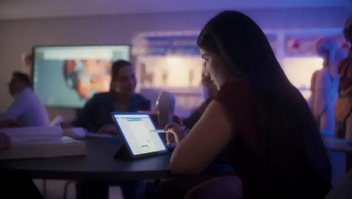 Estudante usando tablet numa sala de aula com modelos de anatomia ao fundo