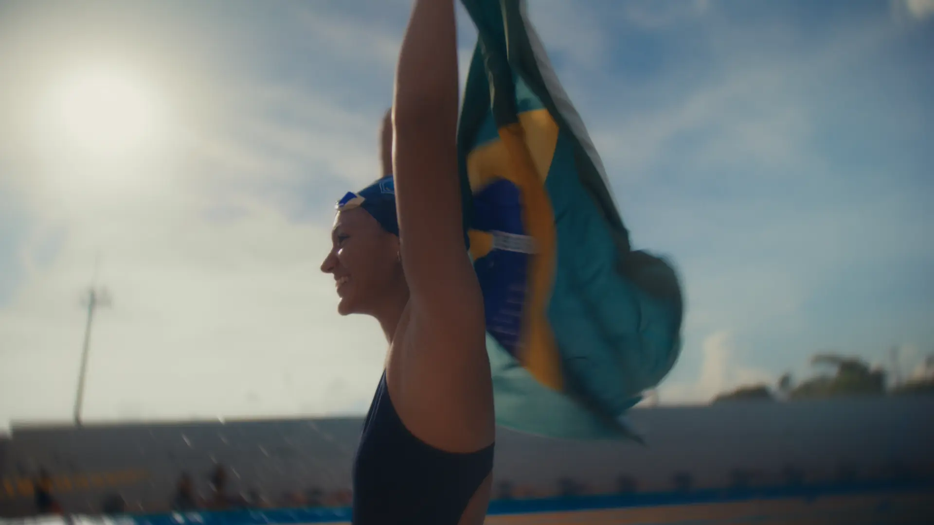 Nadadora com a bandeira do Brasil nas costas, contra o sol