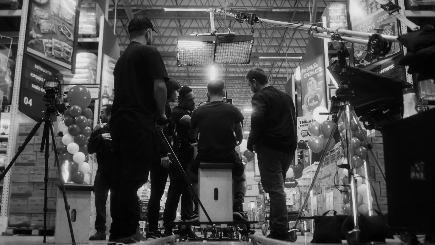 Equipe reunida em volta da câmera no corredor do supermercado